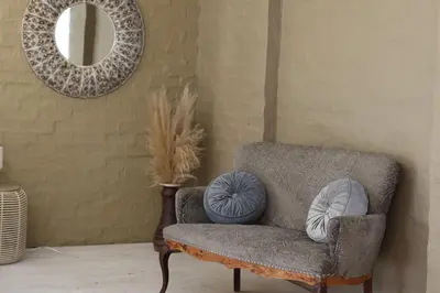 a living room with a chair and a mirror at Shiloh Bush Cottage in Nelspruit