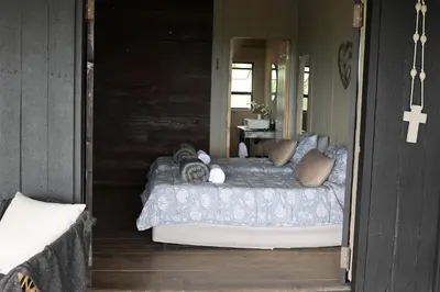 a bedroom with a bed on a porch at Shiloh Bush Cottage in Nelspruit