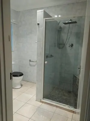 a bathroom with a glass shower with a toilet at Wildflower Haven in Midrand
