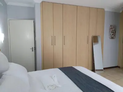 a bedroom with a large white bed and wooden cabinets at Wildflower Haven in Midrand