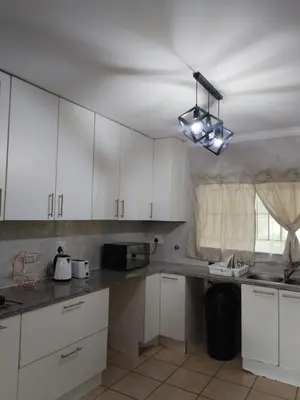 a kitchen with white cabinets and a sink at Wildflower Haven in Midrand