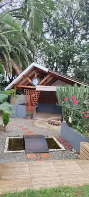 a small building with a clock on it with plants at Wildflower Haven in Midrand