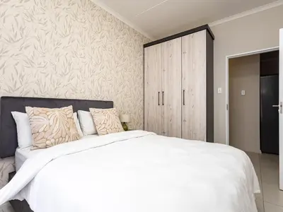 a bedroom with a white bed and a wooden cabinet at BinBins Suite Haven in Midrand