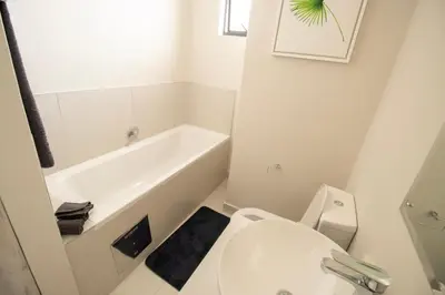 a white bathroom with a toilet and a bath tub at BinBins Suite Haven in Midrand