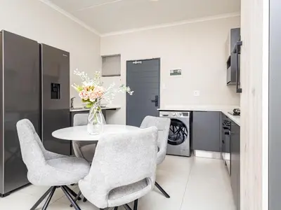 a kitchen with a table with chairs and a vase of flowers at BinBins Suite Haven in Midrand
