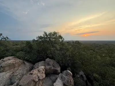 a sunset over a group of rocks and trees at Harmonie Hills in Sukani