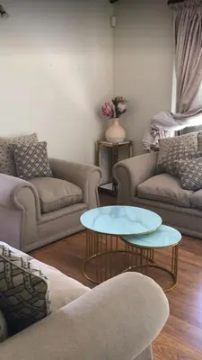 a living room with two couches and two tables at The Cosy Den in Centurion