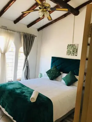 a bedroom with a bed with a ceiling fan at The Cosy Den in Centurion