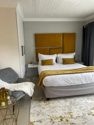 a bedroom with a large bed and a chair at 36 On Blougom in Midrand