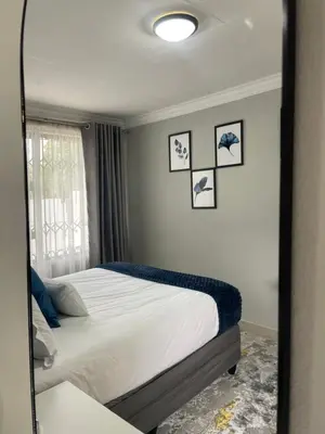 a mirror reflecting a bedroom with a bed and a window at 36 On Blougom in Midrand