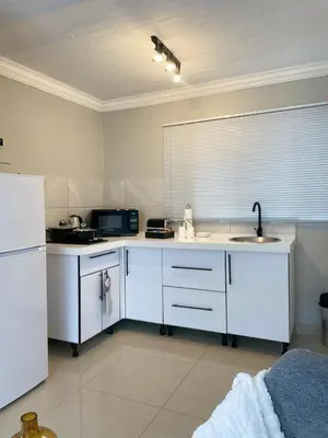 a white kitchen with a sink and a refrigerator at 36 On Blougom in Midrand
