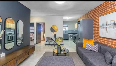 a living room with a couch and a brick wall at Ndlovu Lifestyle Apartments in Midrand
