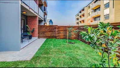 a backyard with a wooden fence next to a building at Ndlovu Lifestyle Apartments in Midrand