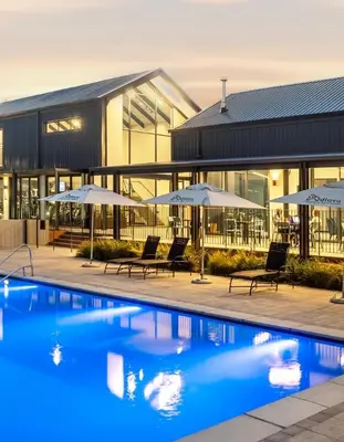 a swimming pool with chairs and umbrellas in front of a building at Ndlovu Lifestyle Apartments in Midrand
