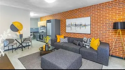 a living room with a couch and a brick wall at Ndlovu Lifestyle Apartments in Midrand