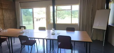 a room with a table and chairs and a board at Greystone Lodge in Dullstroom