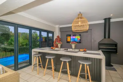 a kitchen with a island with bar stools and a tv at Bunkers Paradis at Pecanwood in Hartbeespoort