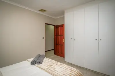 a bedroom with white cabinets and a bed with a blanket at Bunkers Paradis at Pecanwood in Hartbeespoort