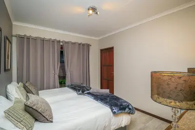 a bedroom with a white bed and a window at Bunkers Paradis at Pecanwood in Hartbeespoort
