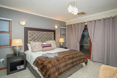 a bedroom with a large bed and two lamps at Bunkers Paradis at Pecanwood in Hartbeespoort