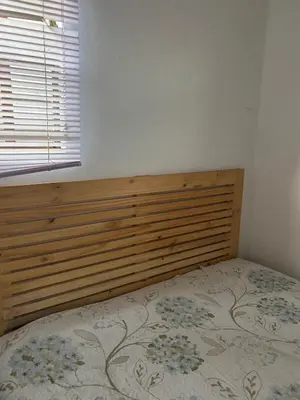 a bedroom with a bed with a wooden headboard and a window at Cabin in Pretoria West in Pretoria