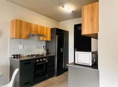 a kitchen with black appliances and wooden cabinets at StayEase Modern Stay in Waterfall in Midrand
