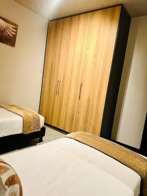 a bedroom with two beds and a wooden cabinet at StayEase Modern Stay in Waterfall in Midrand