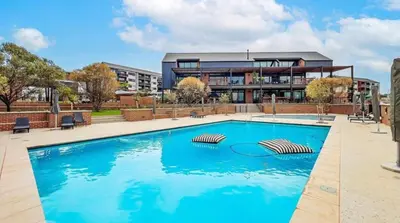 a large blue swimming pool in front of a building at StayEase Modern Stay in Waterfall in Midrand