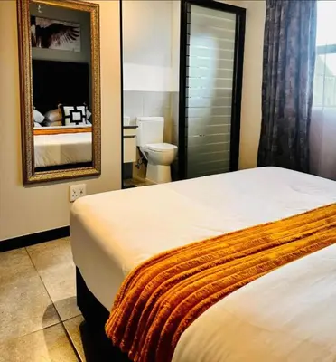 a bedroom with a bed and a toilet and a mirror at StayEase Modern Stay in Waterfall in Midrand