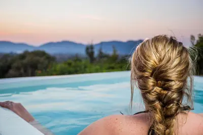 a woman sitting in a swimming pool with her hair at La Montagne Guest Lodge in Hartbeespoort