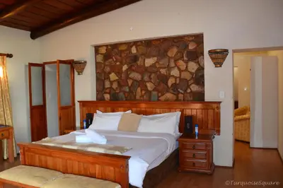 a bedroom with a large bed with a stone wall at La Montagne Guest Lodge in Hartbeespoort