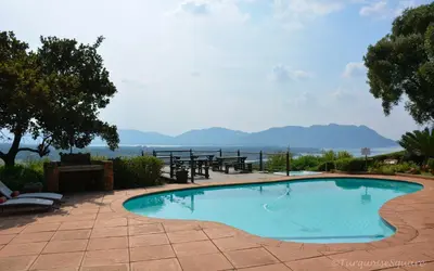 a swimming pool with a table and mountains in the background at La Montagne Guest Lodge in Hartbeespoort