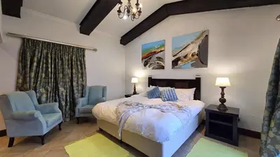 a bedroom with a bed and two blue chairs at Bergendal Lodge in Hydro