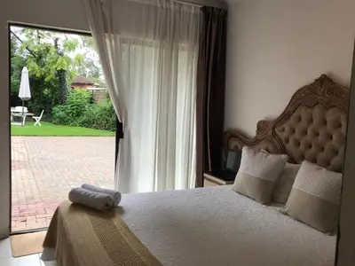 a bedroom with a bed and a large window at Den Accommodation in Olifantsfontein