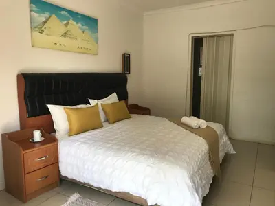 a bedroom with a large bed with yellow pillows at Den Accommodation in Olifantsfontein