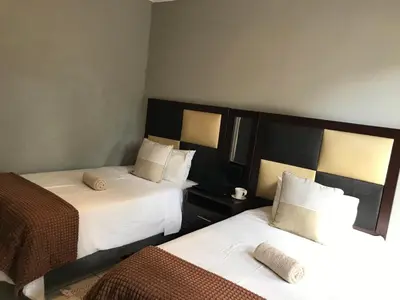 a room with two beds with white sheets and brown blankets at Den Accommodation in Olifantsfontein