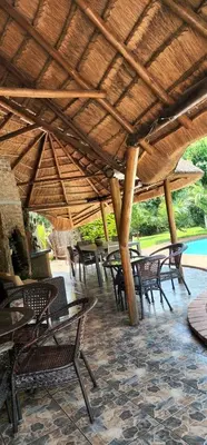 a group of tables and chairs under a wooden roof at Den Accommodation in Olifantsfontein
