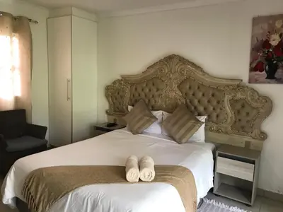 a bedroom with a large bed with two slippers on it at Den Accommodation in Olifantsfontein