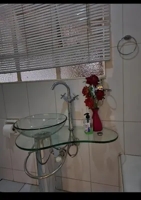 a glass sink in a bathroom with a vase of flowers at Den Accommodation in Olifantsfontein