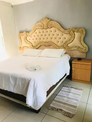 a bedroom with a large bed with a large headboard at Den Accommodation in Olifantsfontein