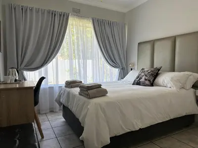 a bedroom with a large bed with a large window at Afrisky Guest House in Kempton Park