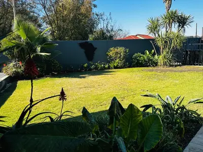 a backyard with a fence and a lawn with plants at Afrisky Guest House in Kempton Park
