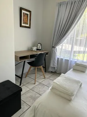 a bedroom with a desk and a chair next to a window at Afrisky Guest House in Kempton Park