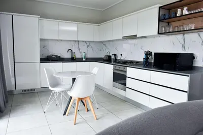 a kitchen with white cabinets and a table and chairs at Fealathome Two Bedroom in Midrand