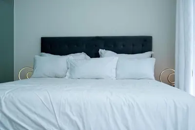 a white bed with a black headboard and white pillows at Fealathome Two Bedroom in Midrand