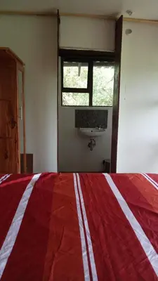 a bedroom with a red and white bed and a sink at Rhulani Treetop Cottage in Marloth Park