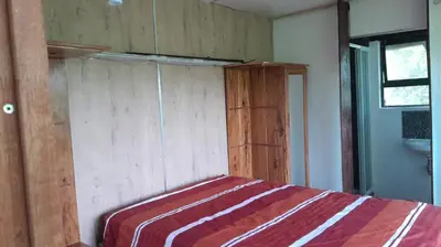 a bedroom with a bed and a wooden wall at Rhulani Treetop Cottage in Marloth Park