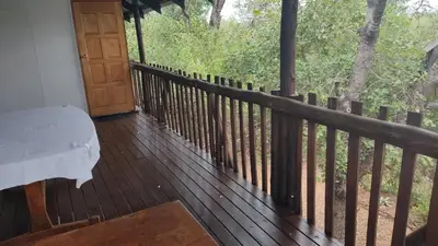 a porch with a bench and a wooden fence at Rhulani Treetop Cottage in Marloth Park