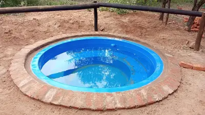 a blue pool in the middle of a dirt field at Rhulani Treetop Cottage in Marloth Park
