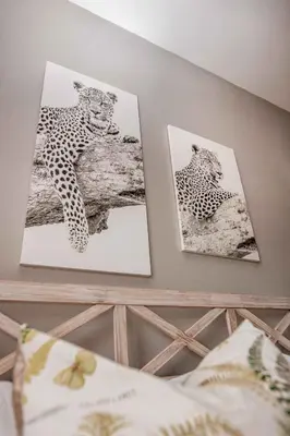 two pictures of cheetahs on a wall above a bed at 10onBrightside-Exp the epitome of country living in Nelspruit
